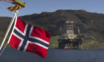 A Norwegian national flag flies from a vessel near the Scarabeo 8 deepwater oil drilling rig, operated by ENI Norge AS, in Olensvag, Norway, on Tuesday, April 3, 2012. The world's seventh-largest oil exporter boasts no net debt, adding to its appeal as an alternative to the debt-riddled euro area. Photographer: Kristian Helgesen/Bloomberg