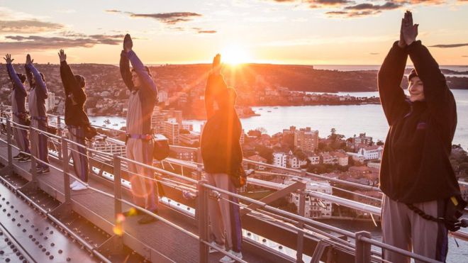 What a view! These guys do a bit of yoga at sunrise on top of the Sydney Harbour Bridge!