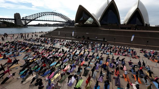 Yoga fans in Australia bend and flex in front of the world famous Sydney Harbour Bridge and Sydney Opera House.